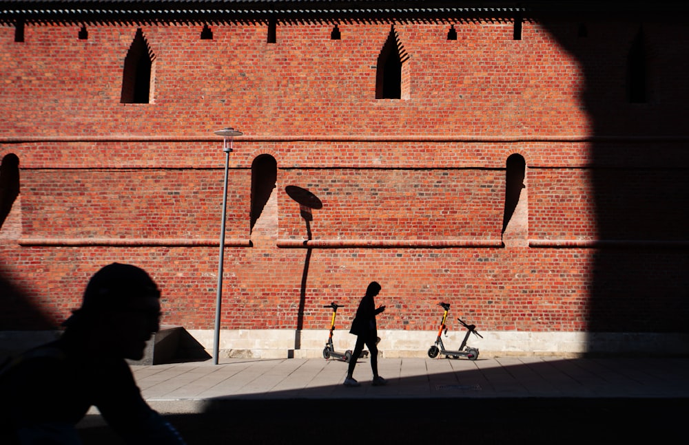 a person walking down a sidewalk next to a brick wall