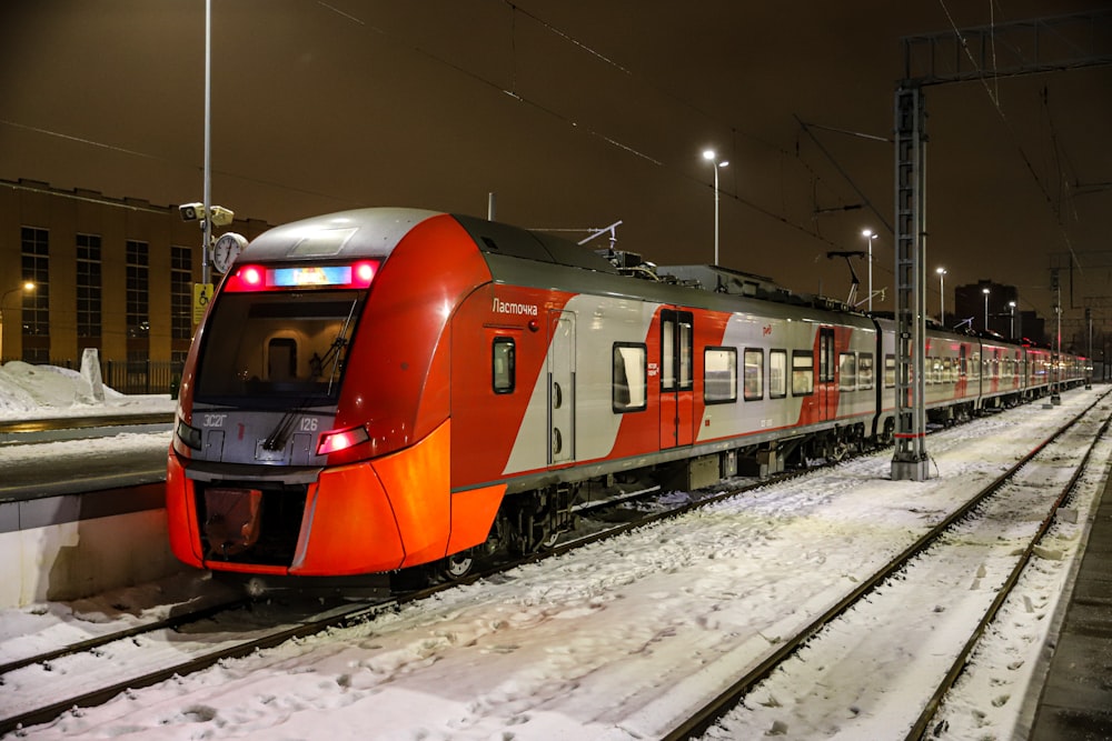 a red and white train traveling down train tracks