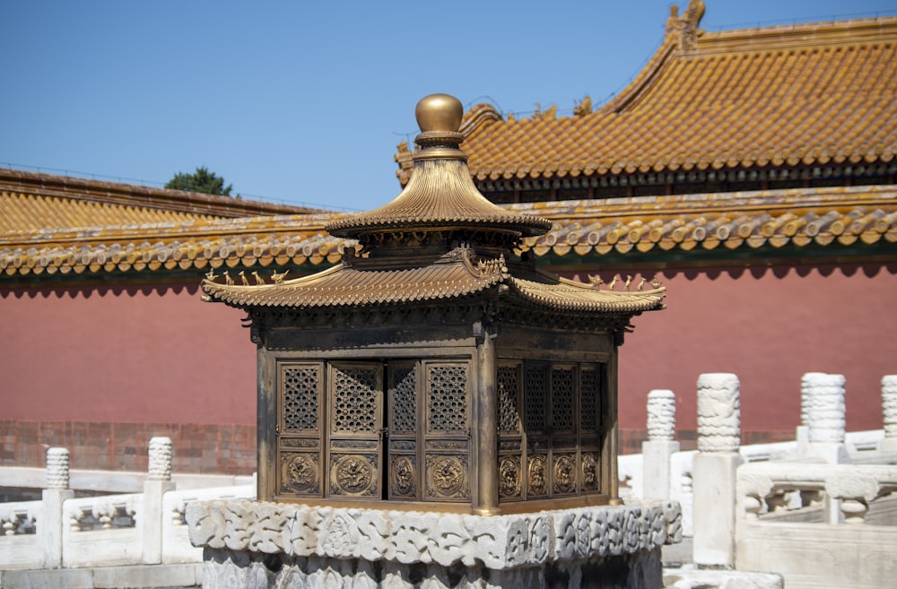 a building with a golden roof and a red wall behind it