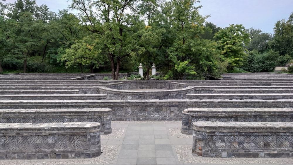 a stone structure with benches and trees in the background