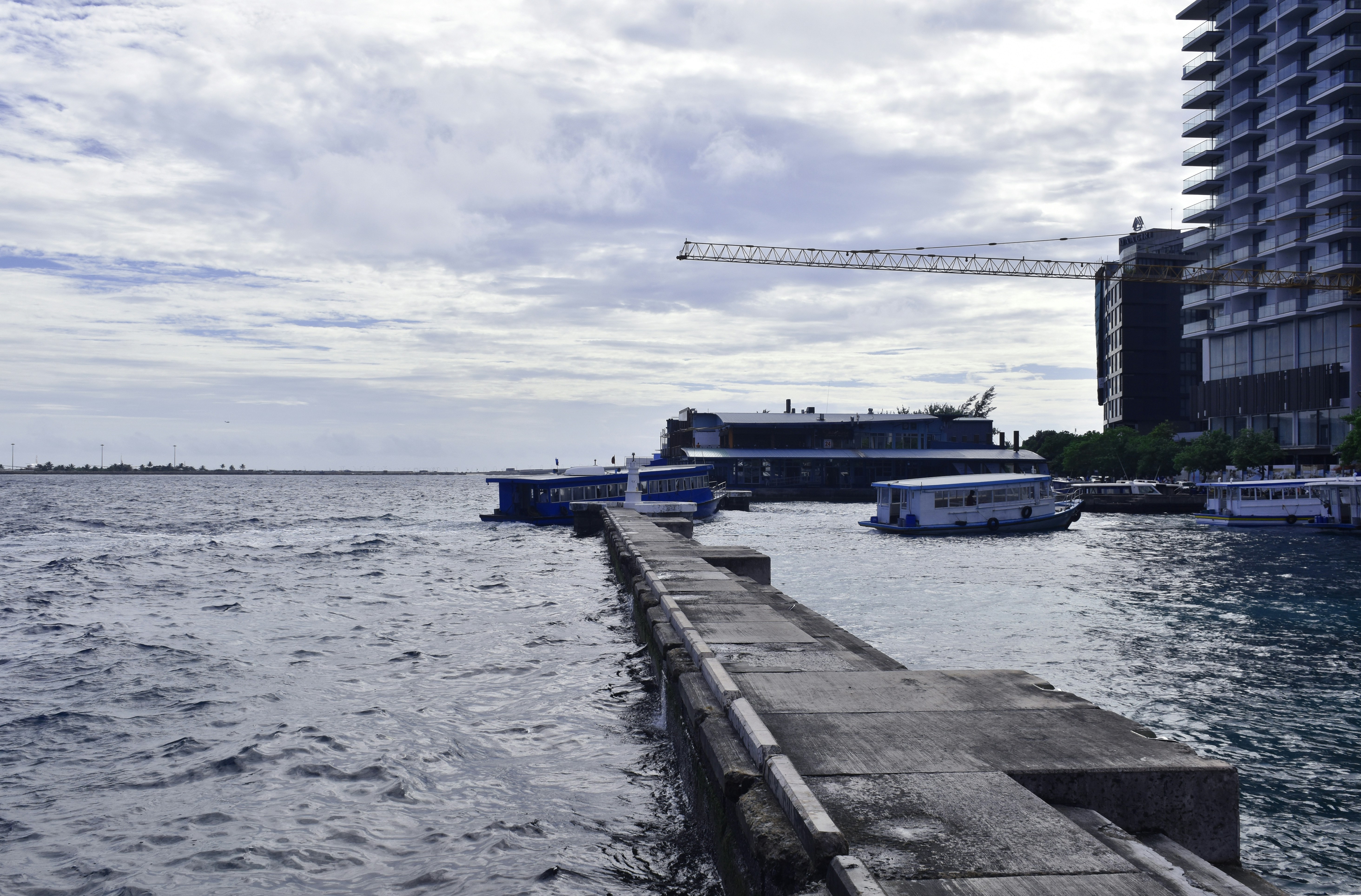 a harbor with boats and a crane in the background, 