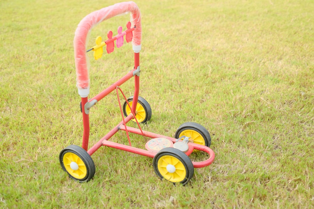 a pink and yellow cart sitting on top of a lush green field