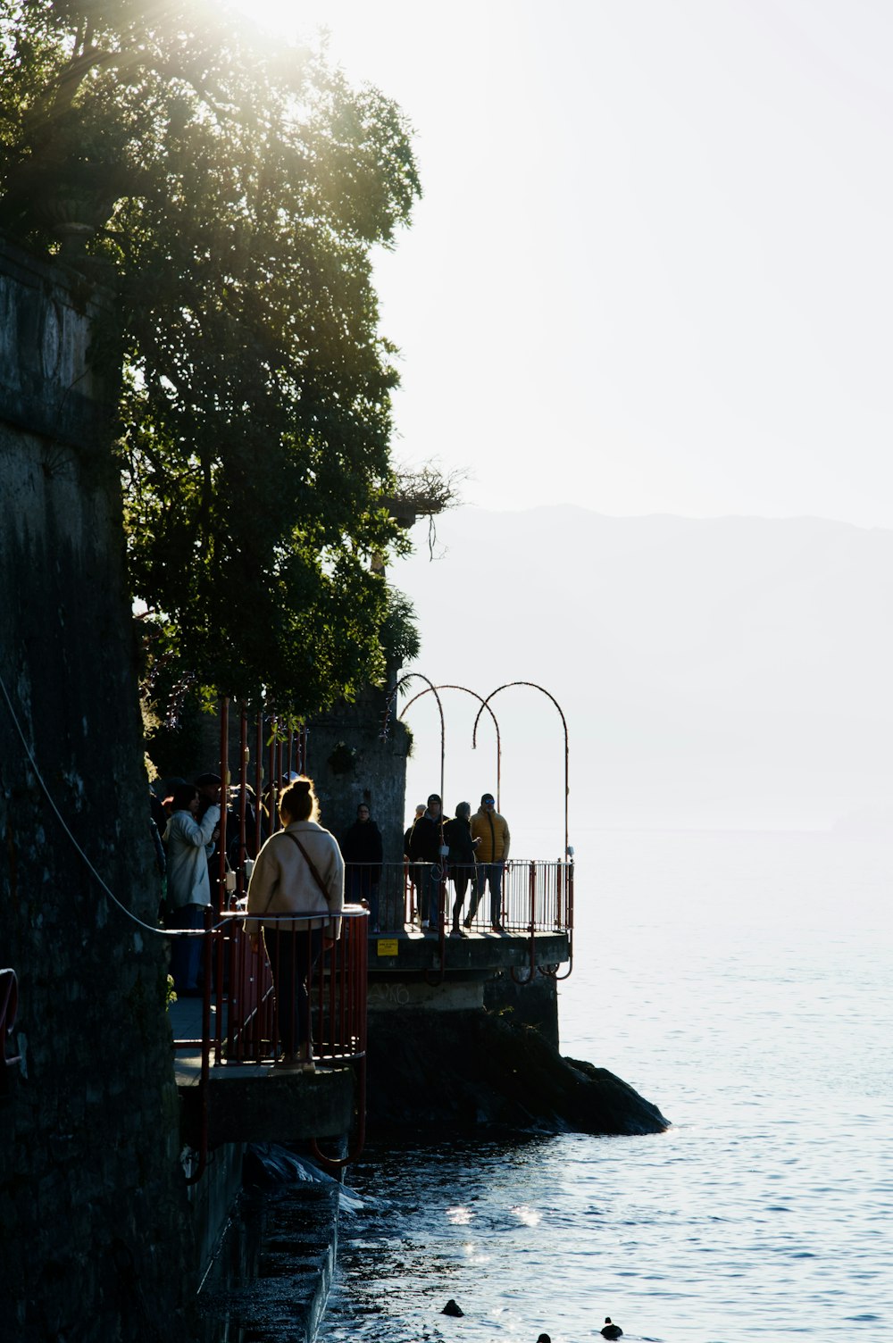 a group of people standing on a pier next to a body of water