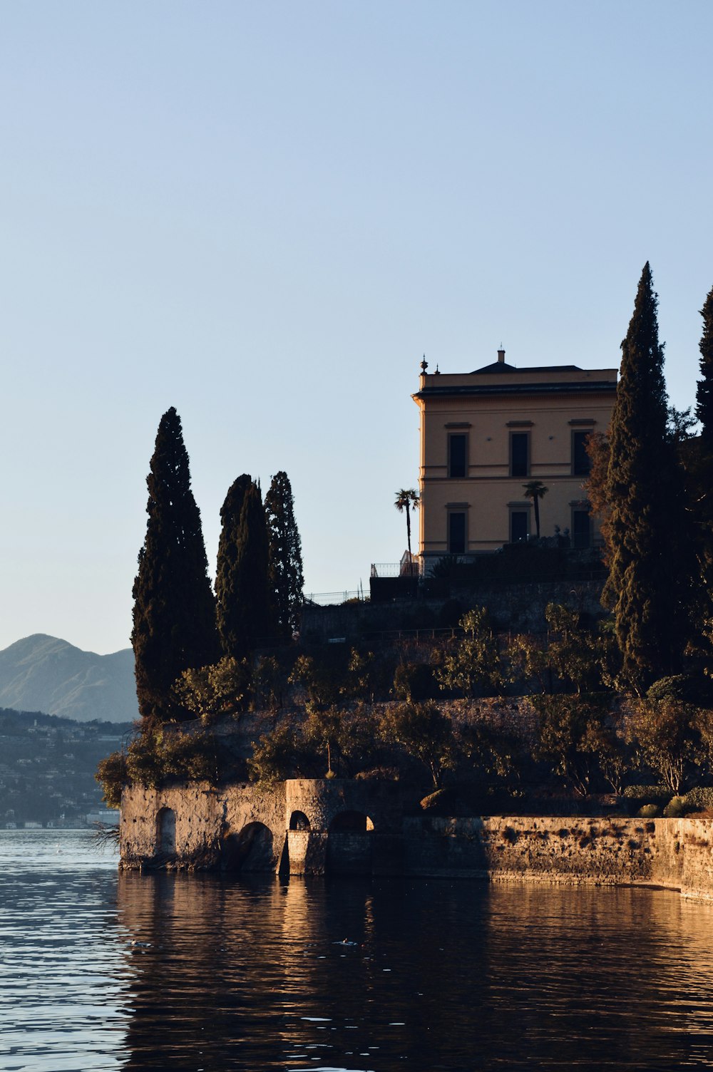 a house sitting on top of a hill next to a body of water