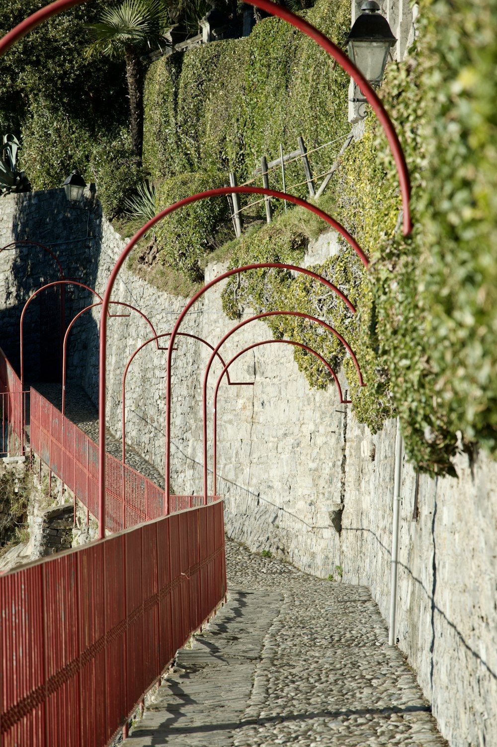 a stone path with a red fence and a light pole