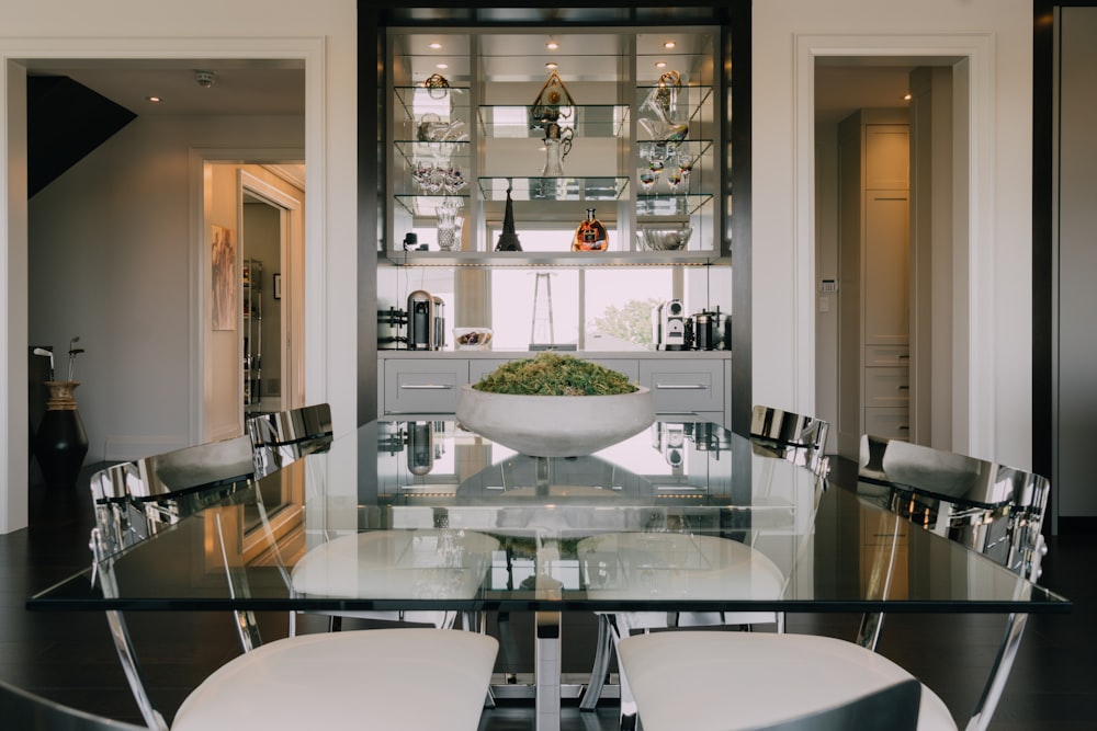 a dining room table with chairs and a bowl of flowers