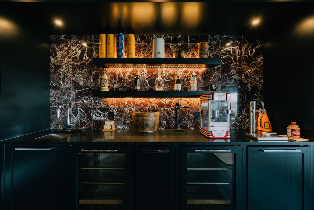 a kitchen with black cabinets and marble counter tops