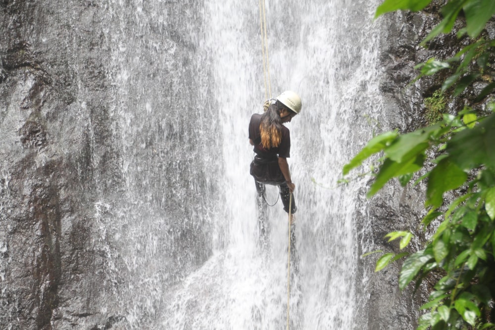 a man on a rope in front of a waterfall