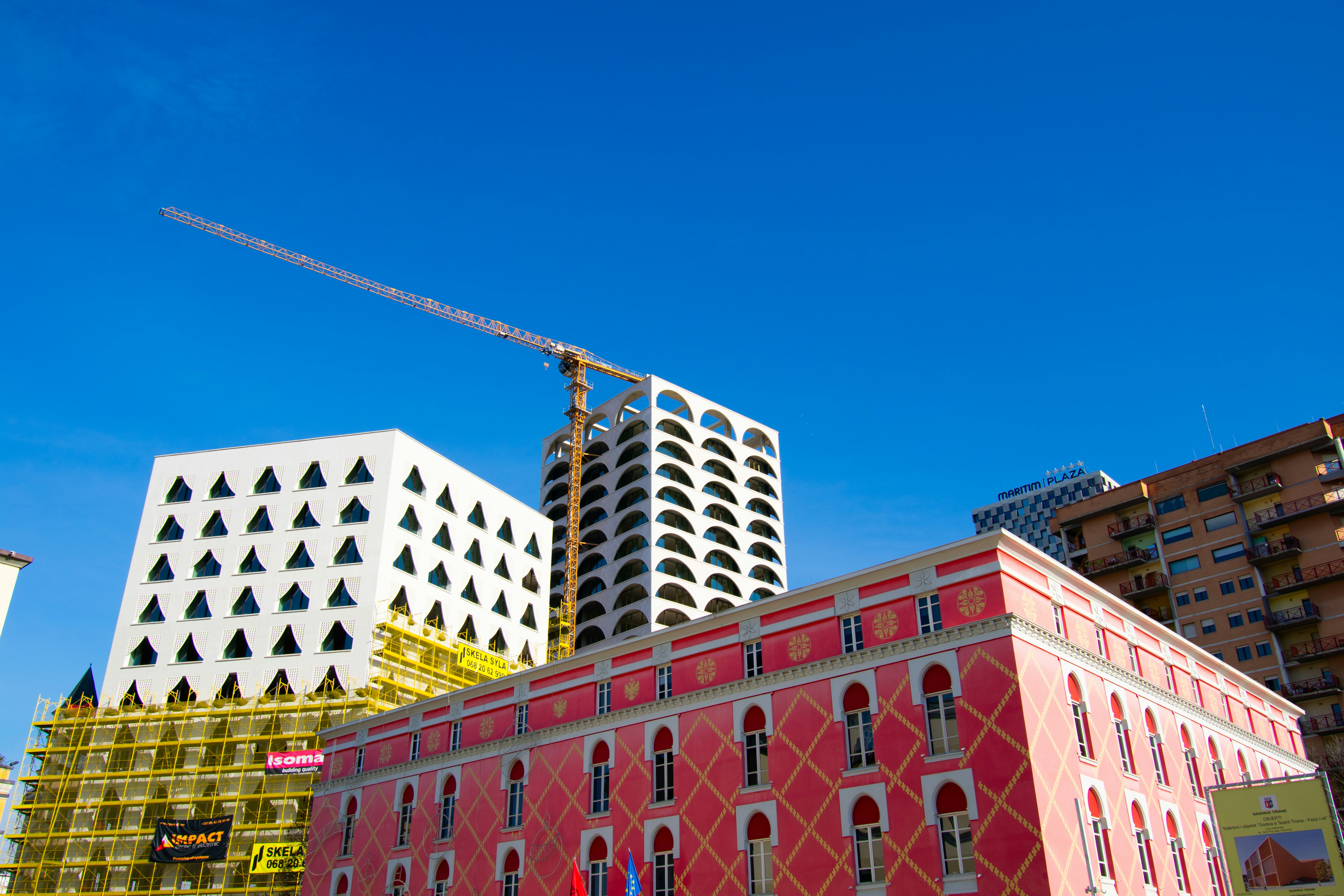 a building with a crane on top of it next to other buildings