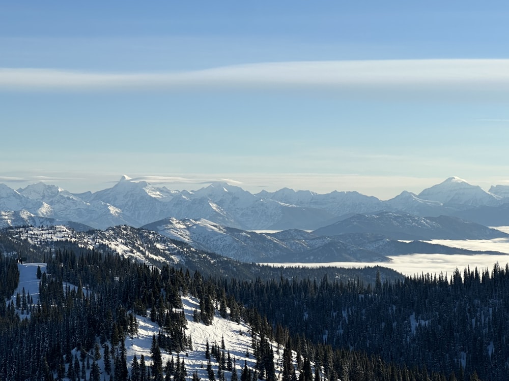 a view of a snowy mountain range with trees and mountains in the background