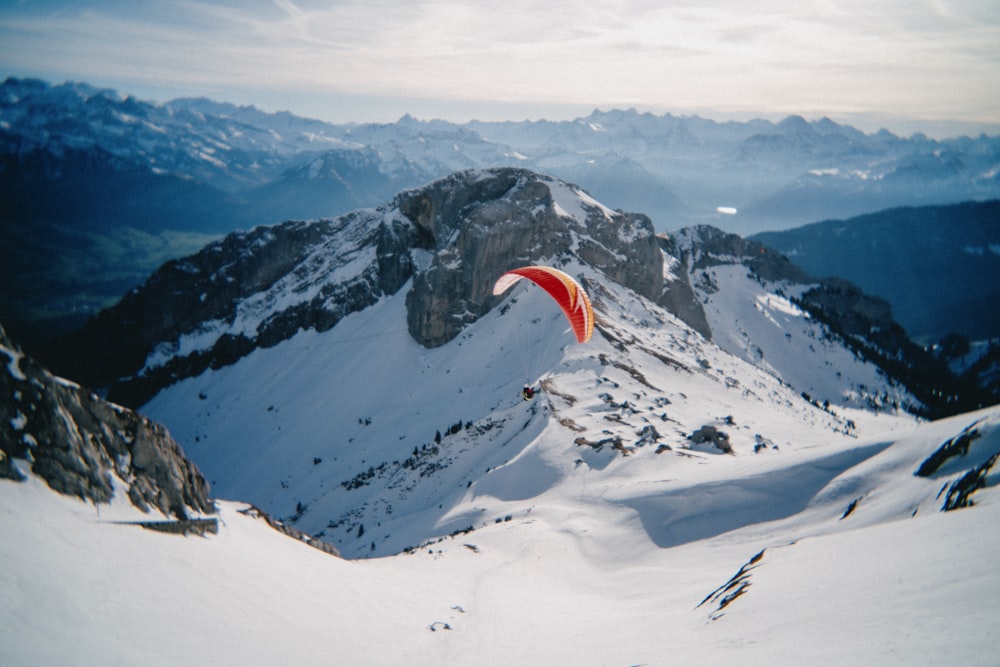 a paraglider flying over a snow covered mountain