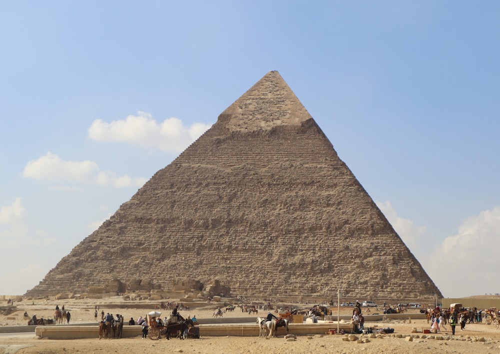 a group of people riding horses in front of a pyramid