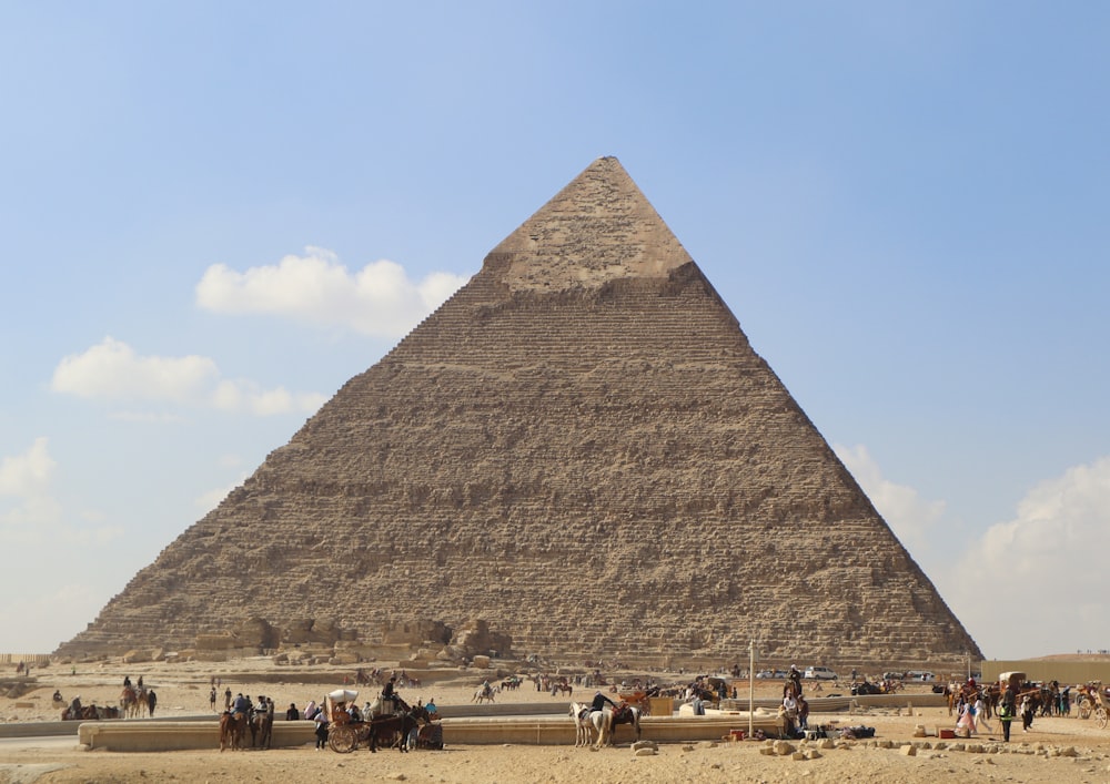 um grupo de pessoas montando cavalos em frente a uma pirâmide