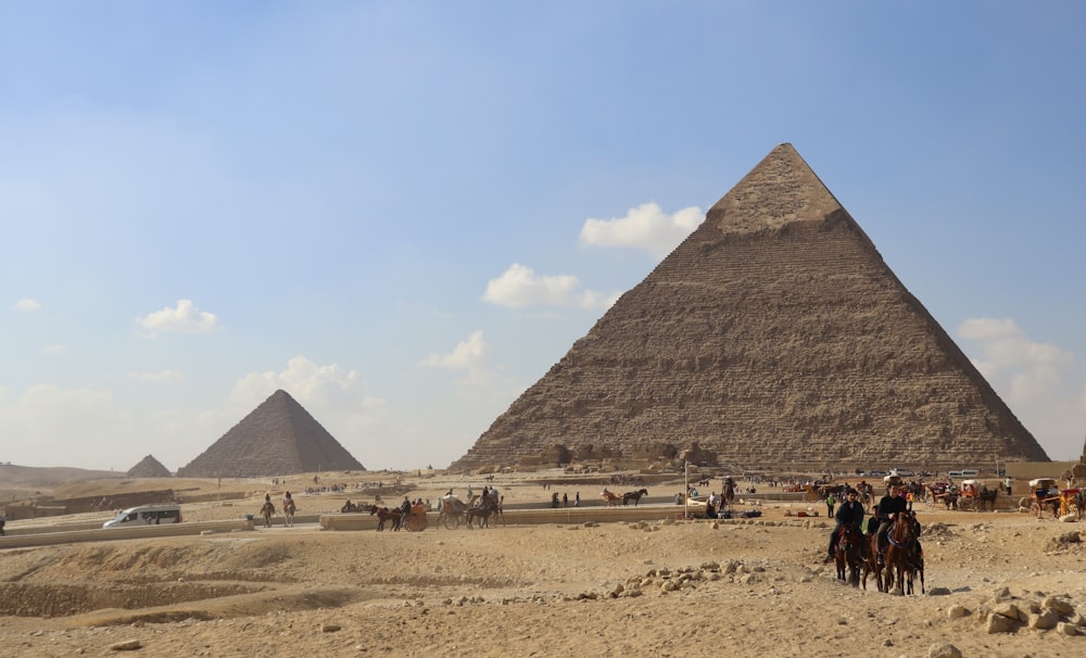 um grupo de pessoas montando cavalos em frente a uma pirâmide
