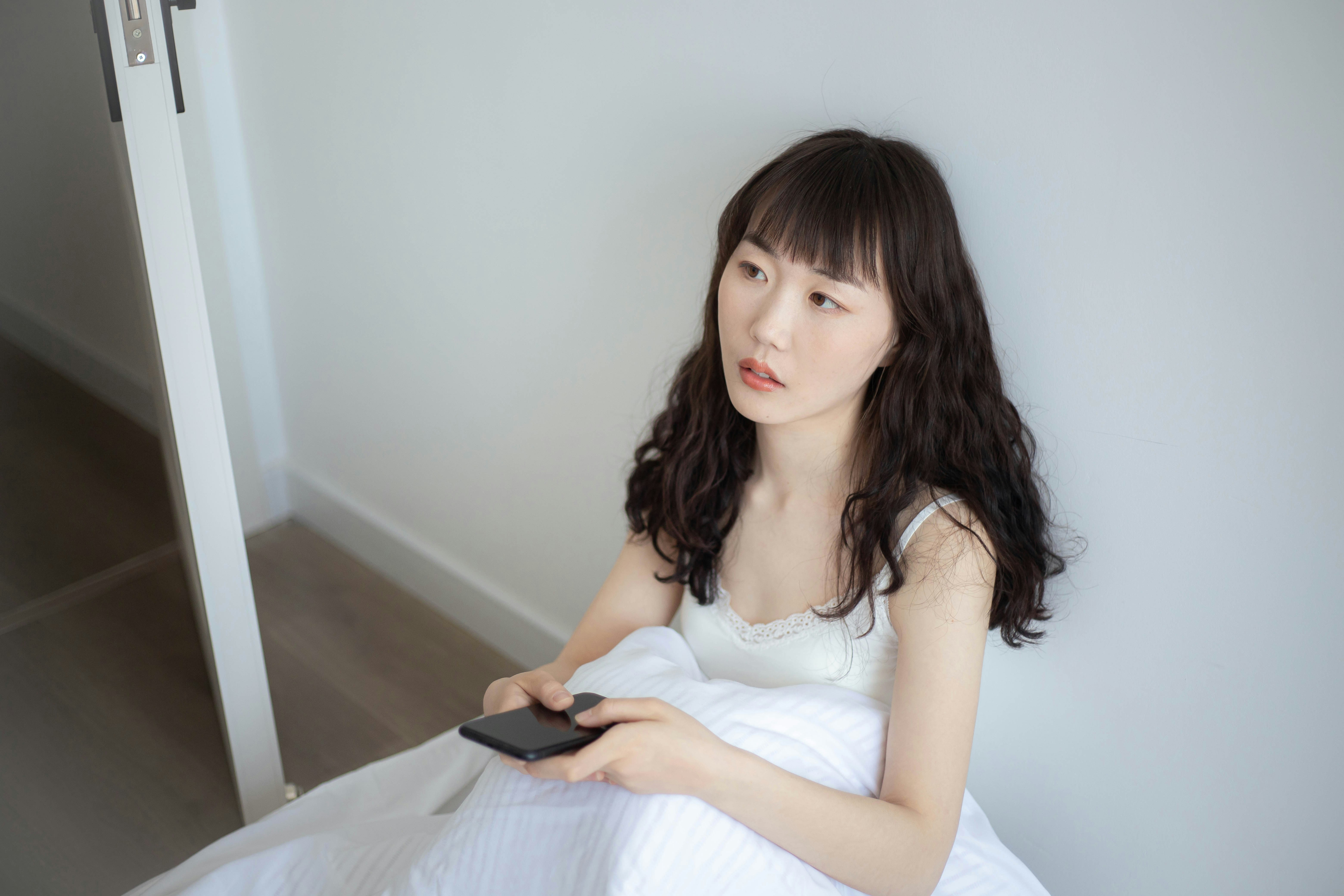 a woman sitting on a bed holding a remote control