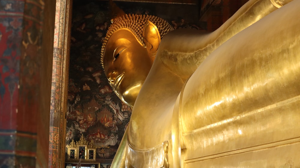 une grande statue de Bouddha doré assise à l’intérieur d’un bâtiment