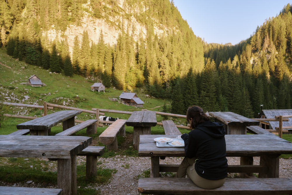 a person sitting at a picnic table in the mountains