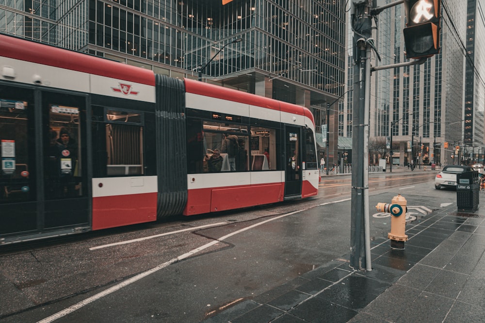 a red and white train on a city street