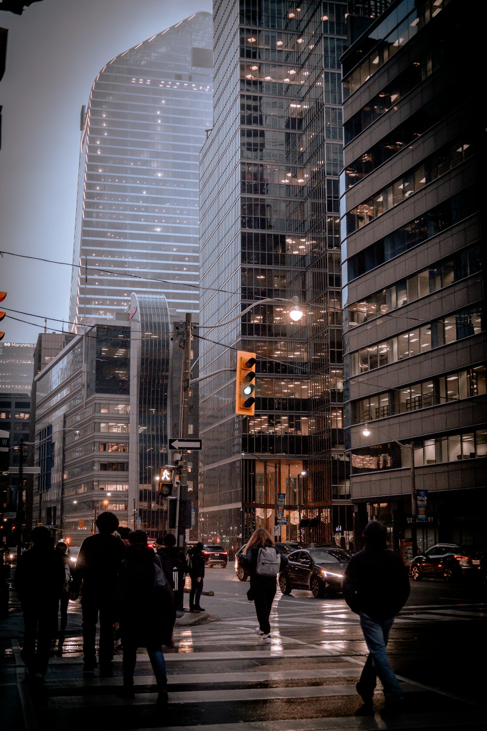 a group of people crossing a street in front of tall buildings