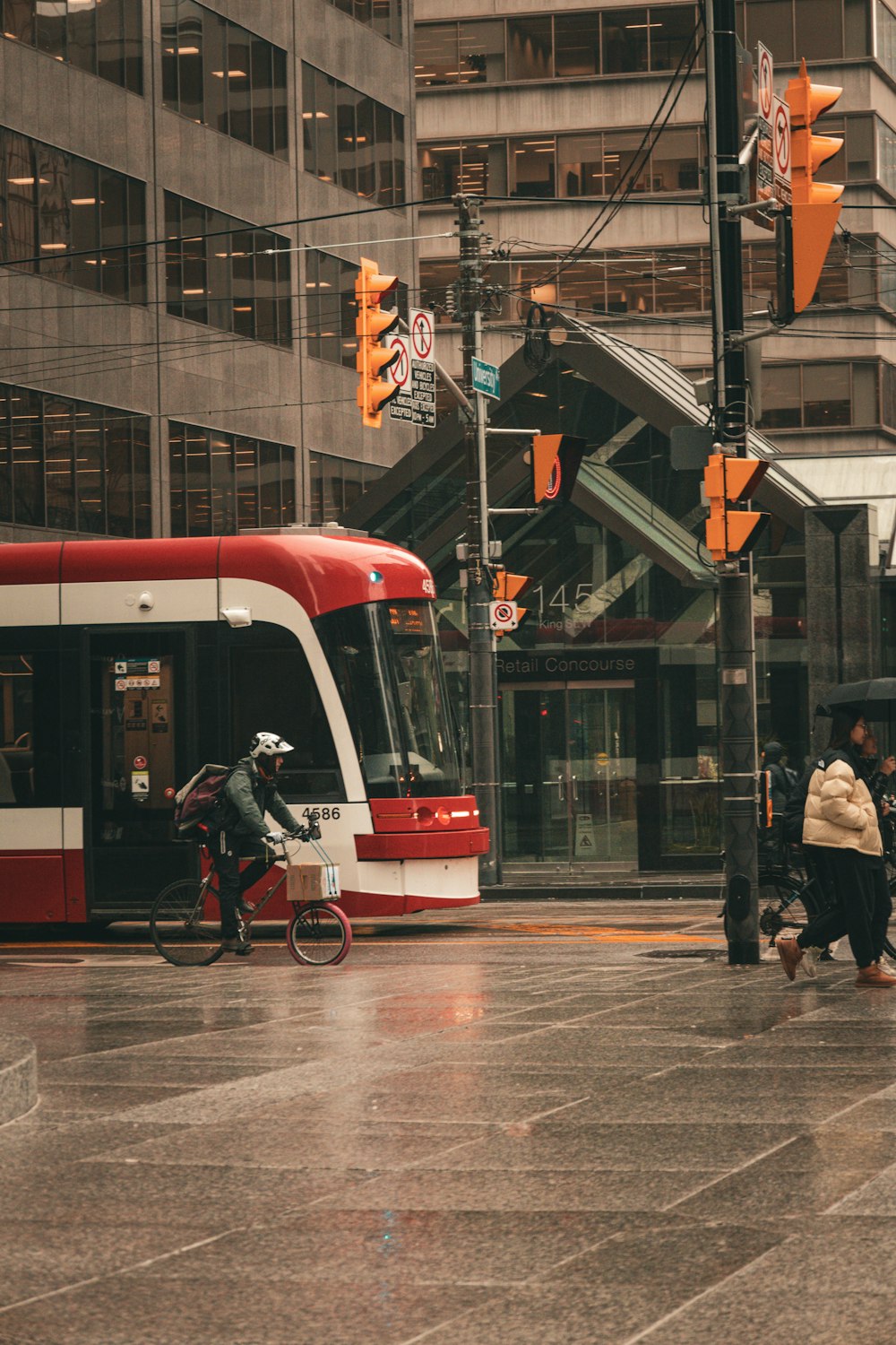 a red and white bus driving down a street next to tall buildings