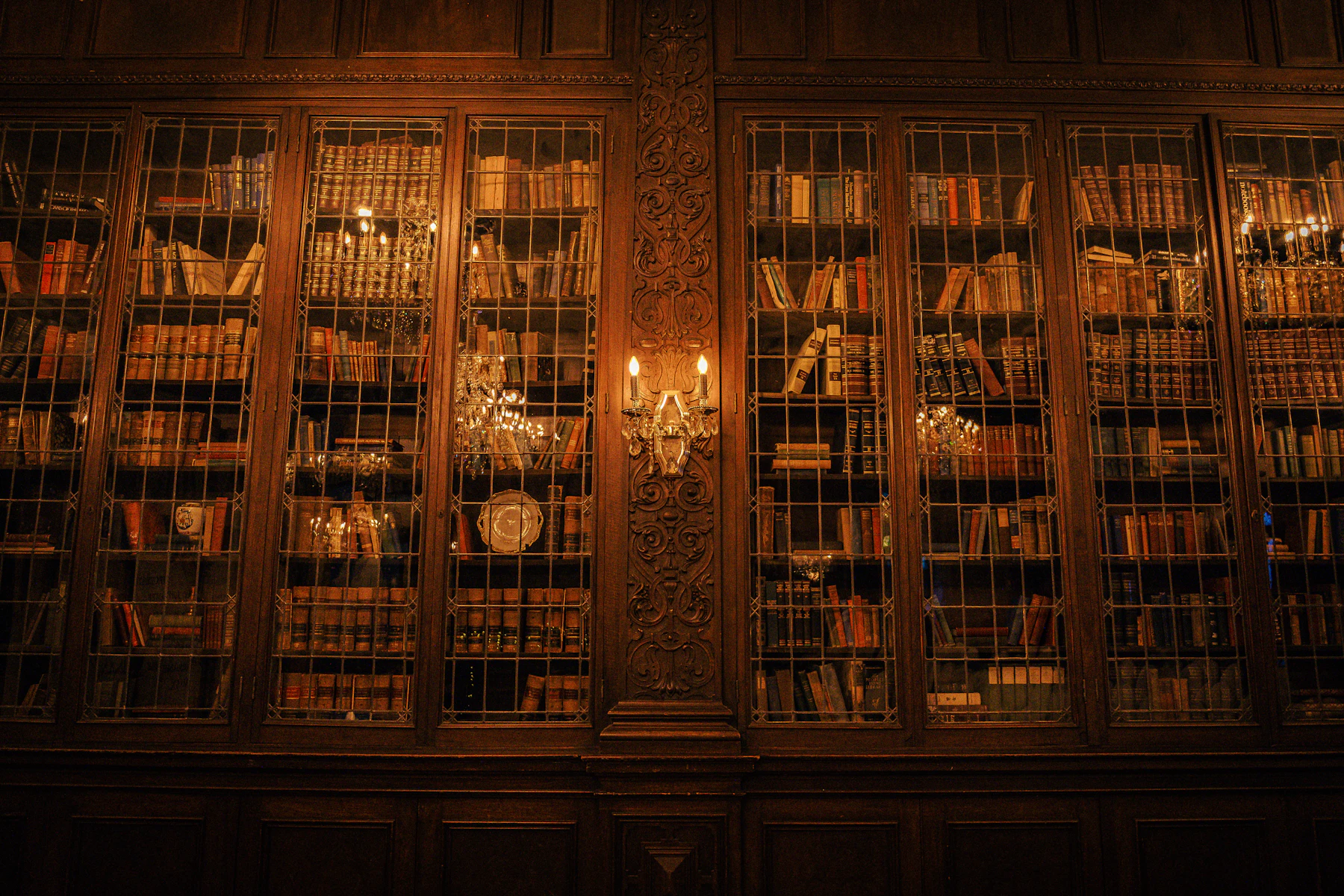 A two-storey library of wooden shelves under warm chandelier light