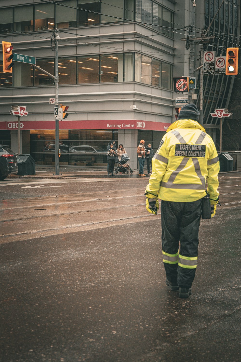a man in a yellow jacket walking down a street
