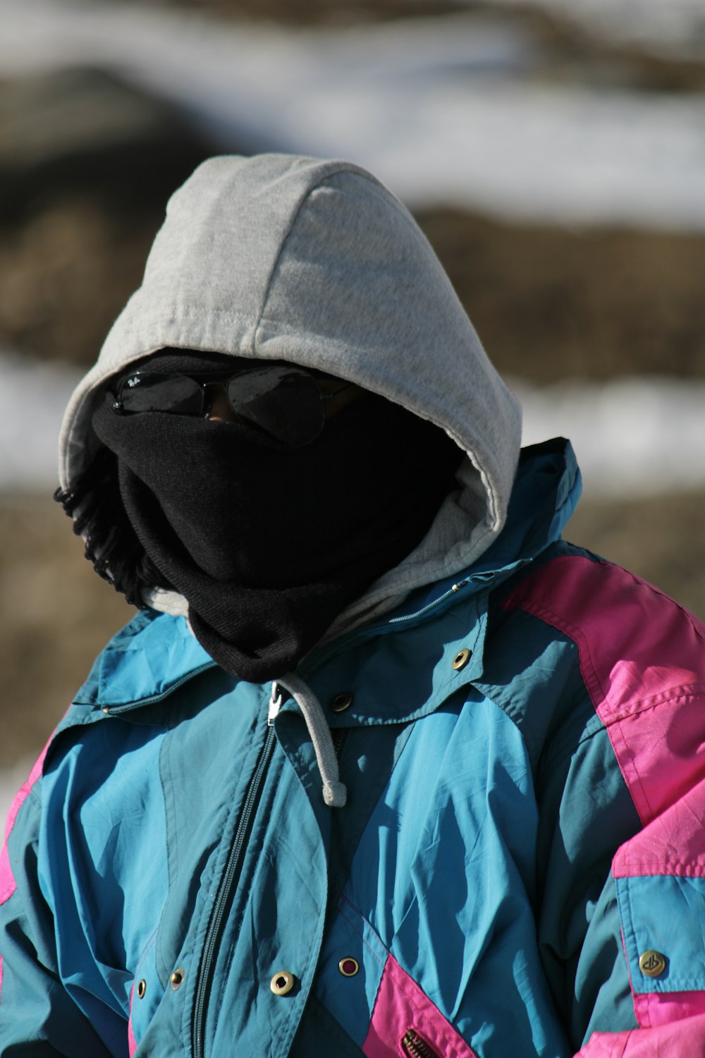 a person wearing a blue and pink jacket with a hood