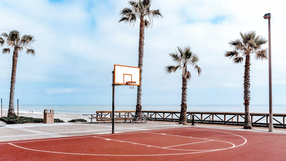 un terrain de basket à côté d’une plage avec des palmiers