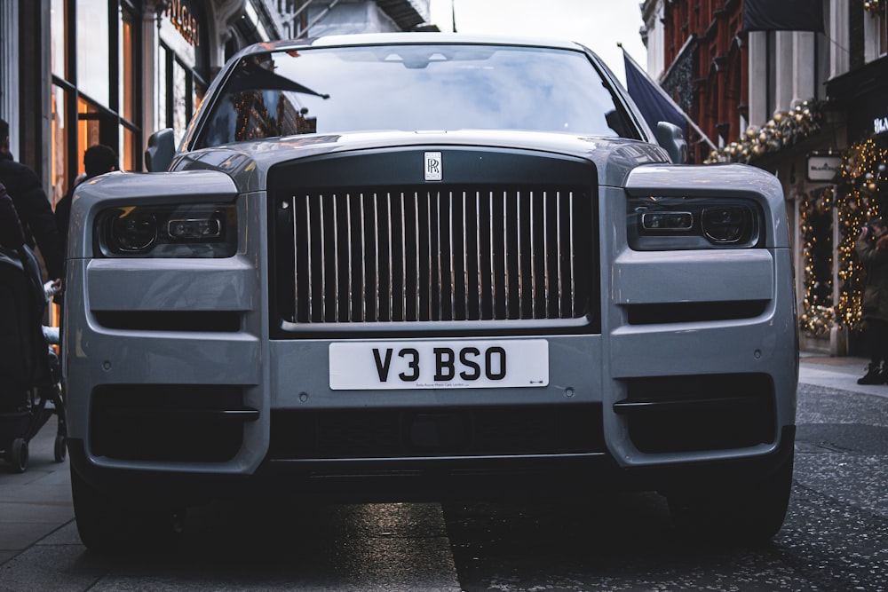 a grey rolls royce parked on the side of a street