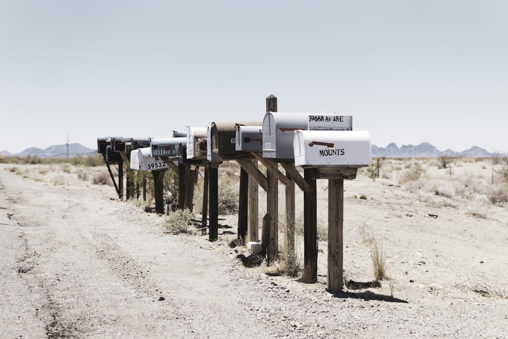 a row of mail boxes sitting on the side of a dirt road