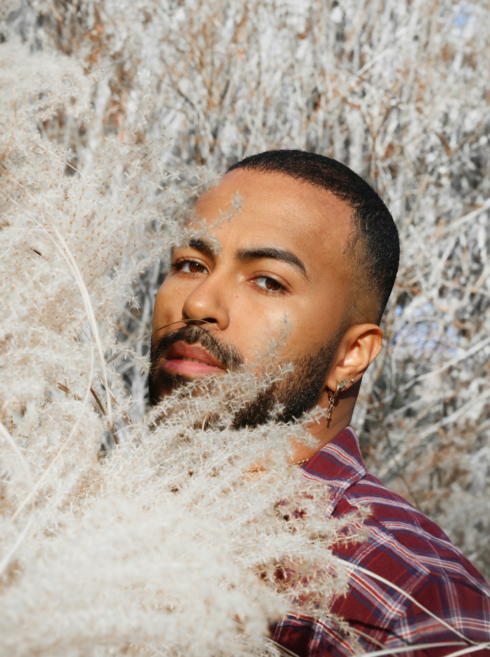 a man with a beard standing in a field of grass