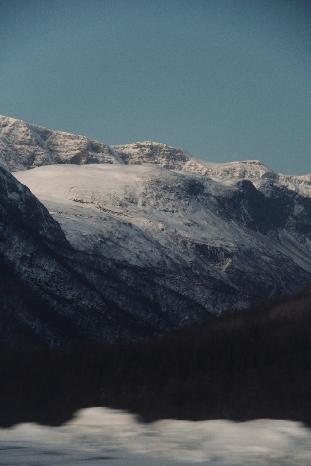 a snow covered mountain range with trees in the foreground