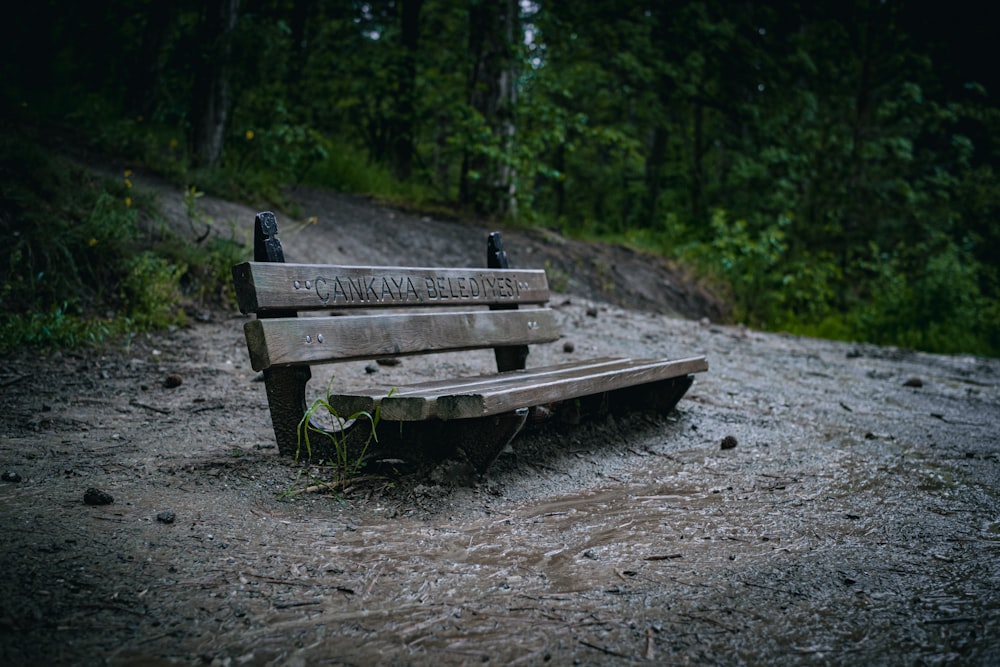una panchina di legno seduta in cima a una strada fangosa