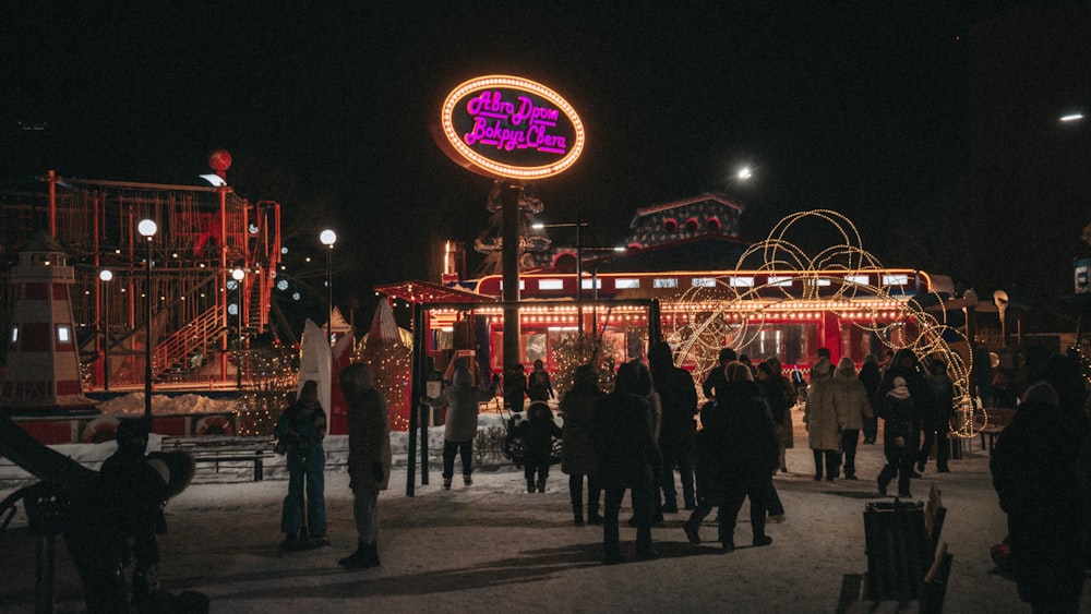 Una multitud de personas de pie alrededor de un carnaval por la noche