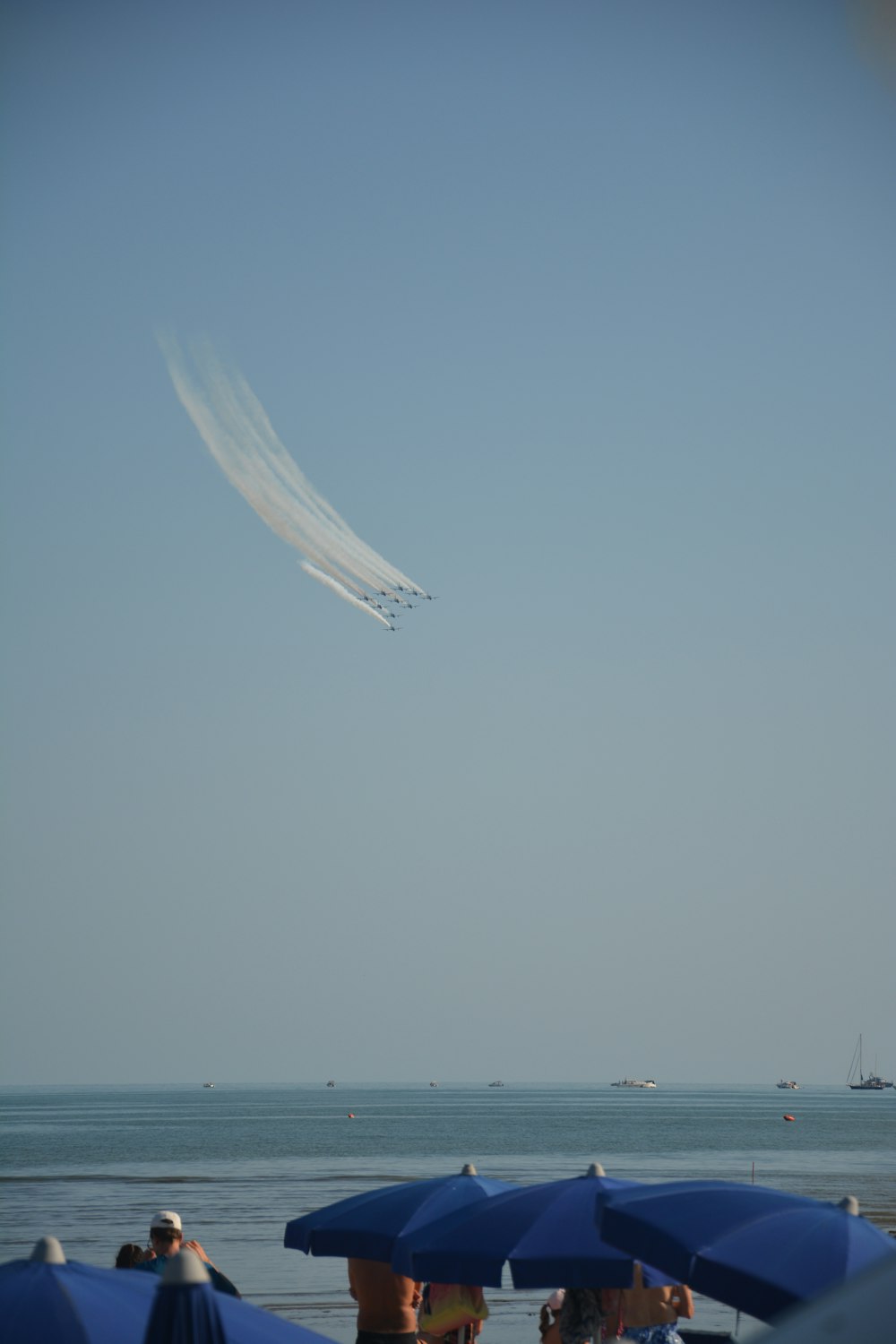 a plane is flying over a beach with umbrellas