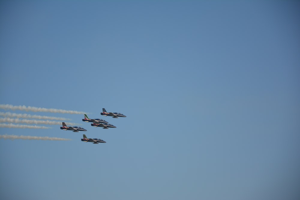 a group of jets flying through a blue sky