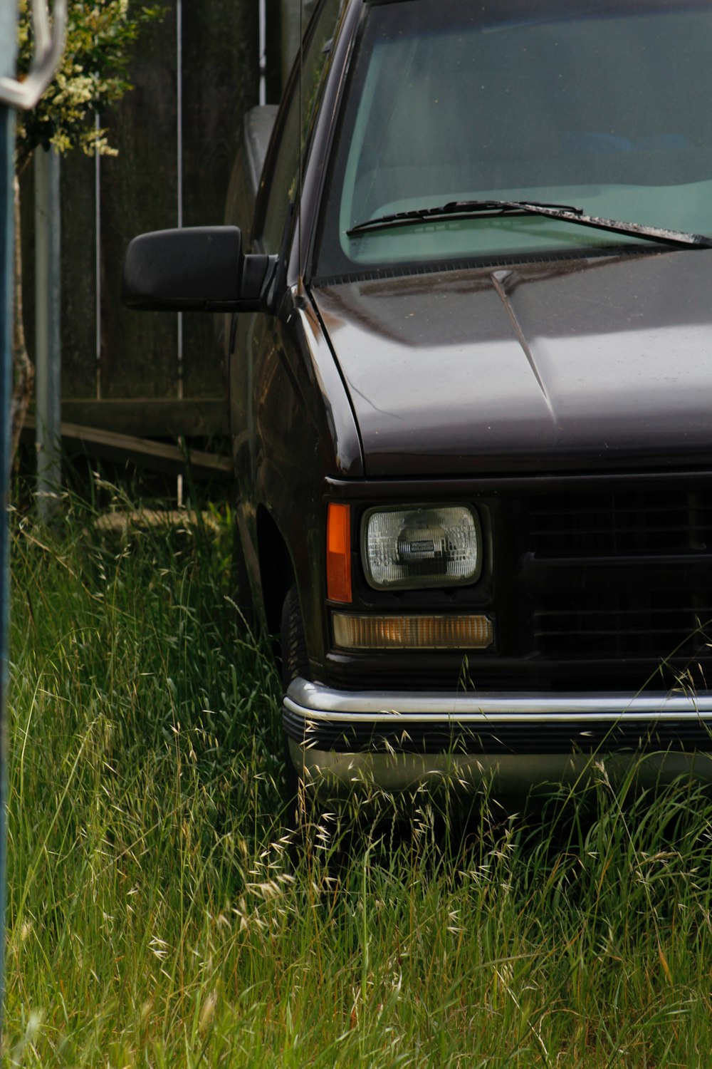 a black truck parked in the grass next to a fence