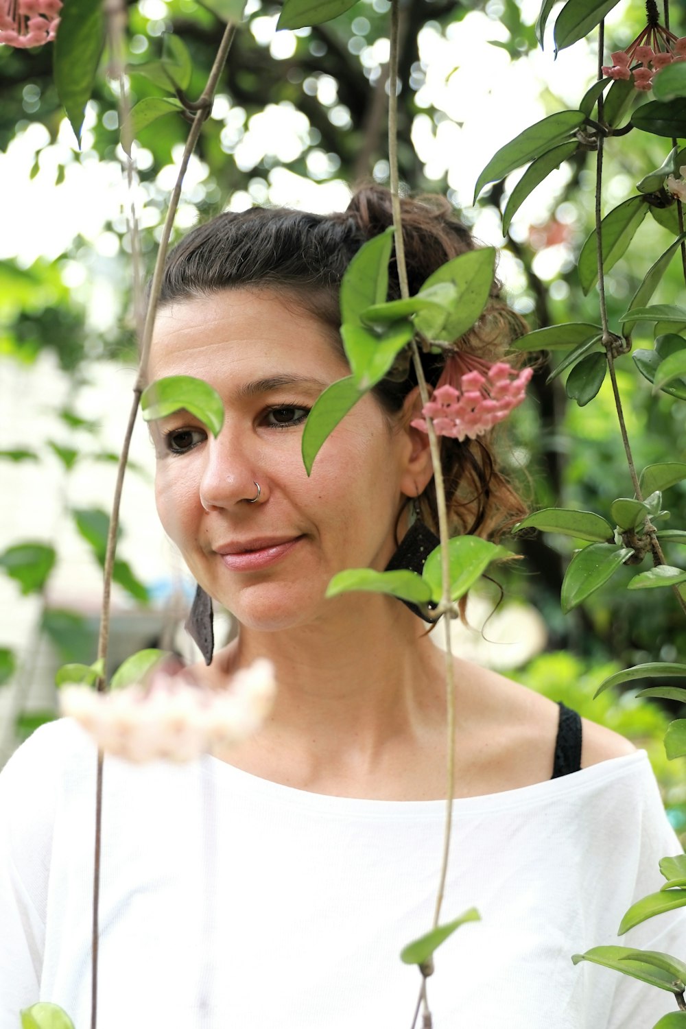 a woman in a white top standing under a tree