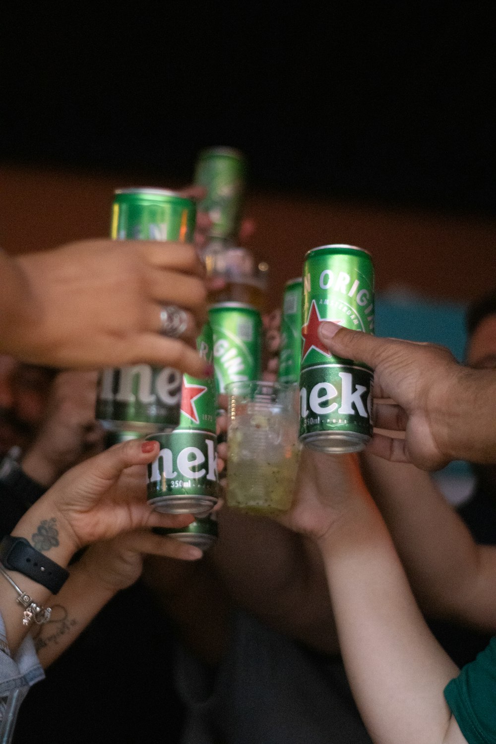 a group of people holding up cans of beer