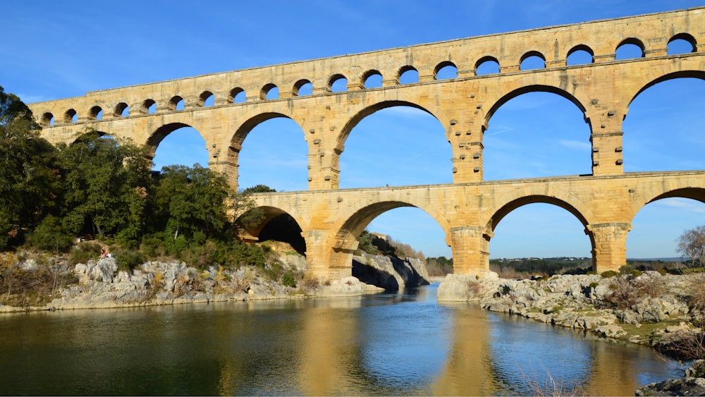 a large stone bridge over a river next to a forest