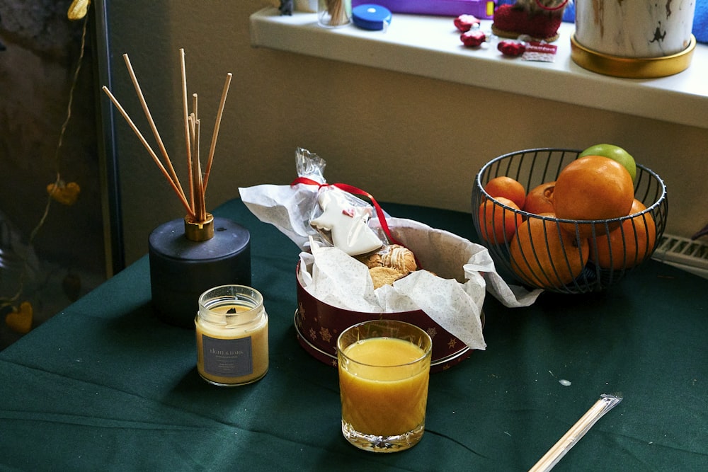 a table topped with a basket of fruit next to a cup of orange juice