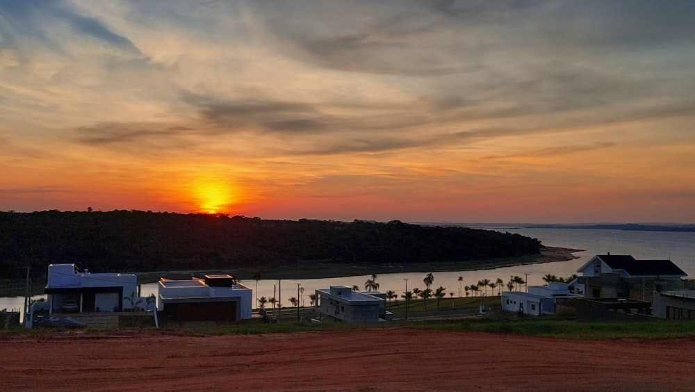 a sunset over a body of water with houses in the foreground