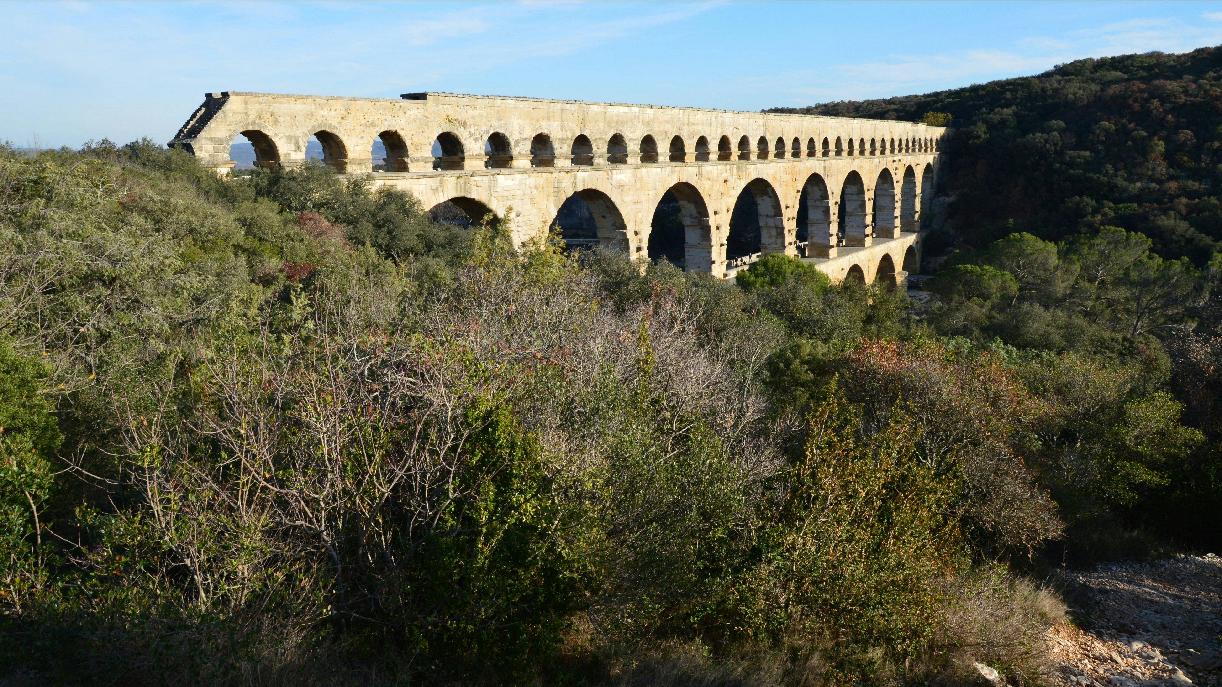 a large stone bridge over a lush green hillside