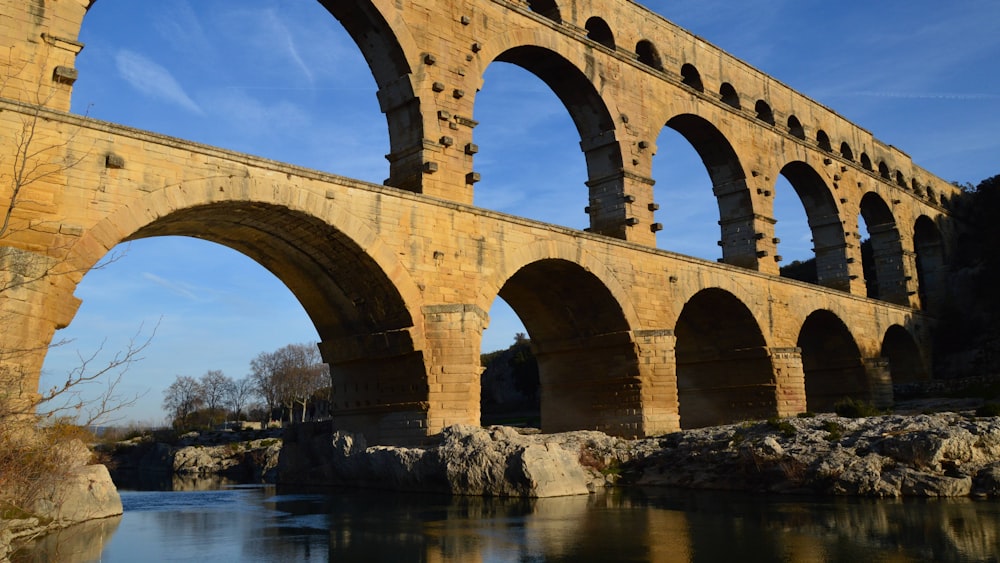 a large stone bridge over a river under a blue sky