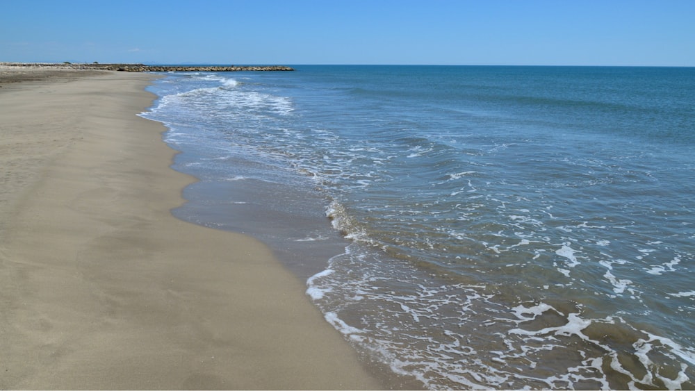 a sandy beach with waves coming in to the shore