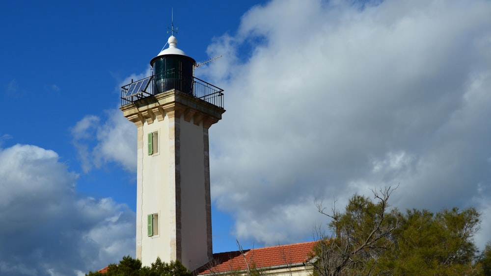 a white and green lighthouse on a cloudy day