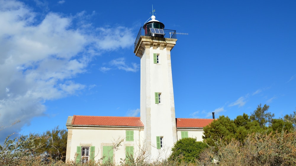 a white lighthouse with a red roof and green shutters