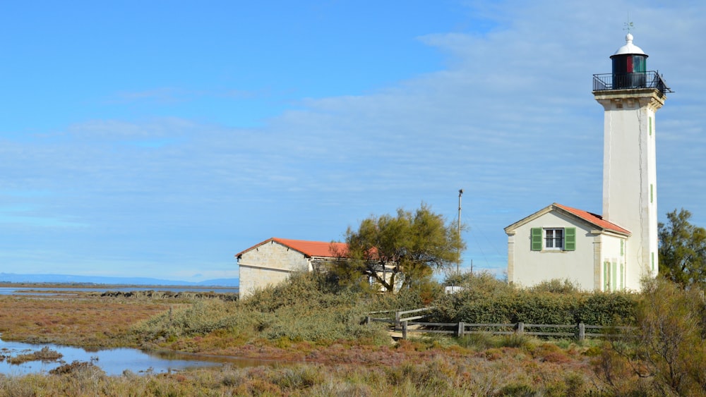 a white lighthouse with a red roof in a field