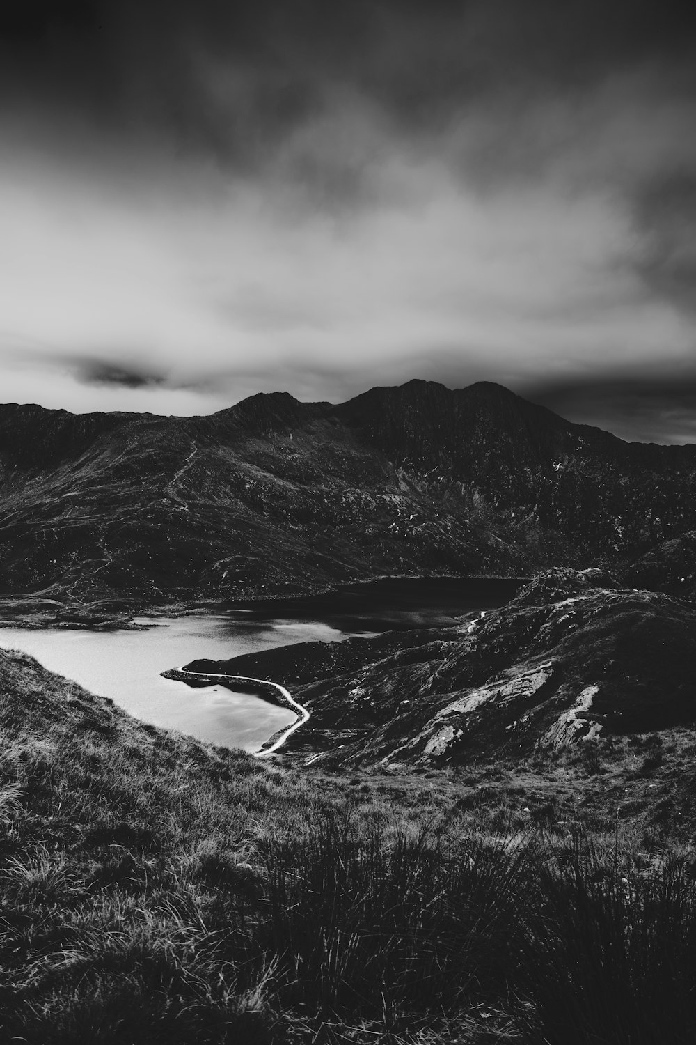 a black and white photo of mountains and a lake