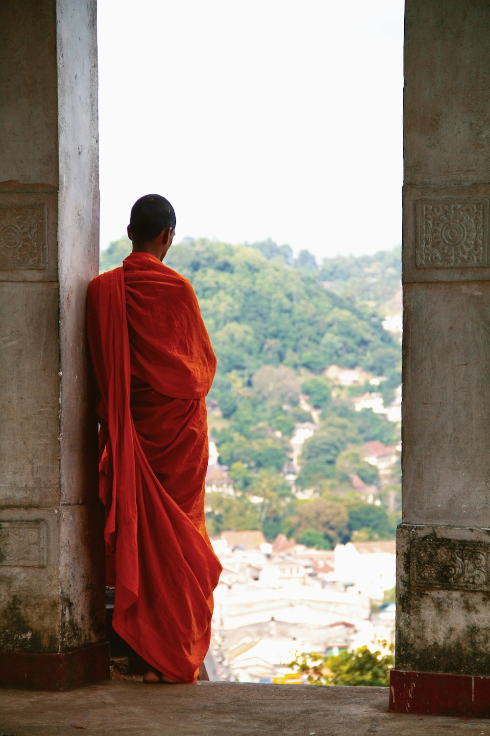 a person in a red robe looking out of a doorway
